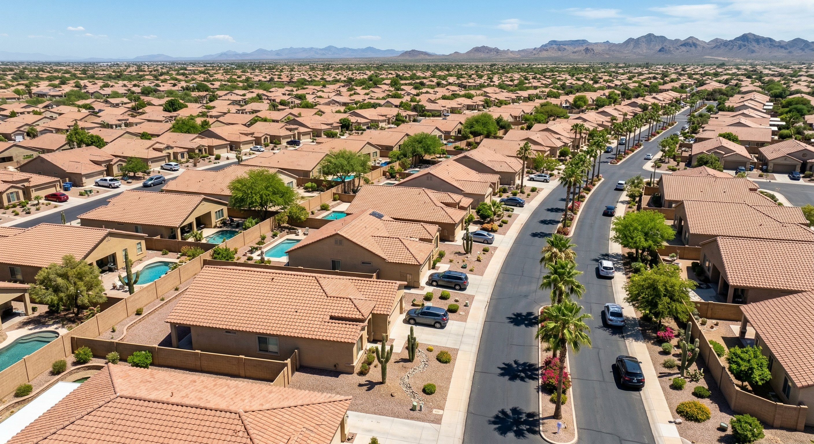 Aerial drone view of a sun-drenched Peoria Arizona residential neighborhood with stucco homes, tile roofs, and desert landscaping