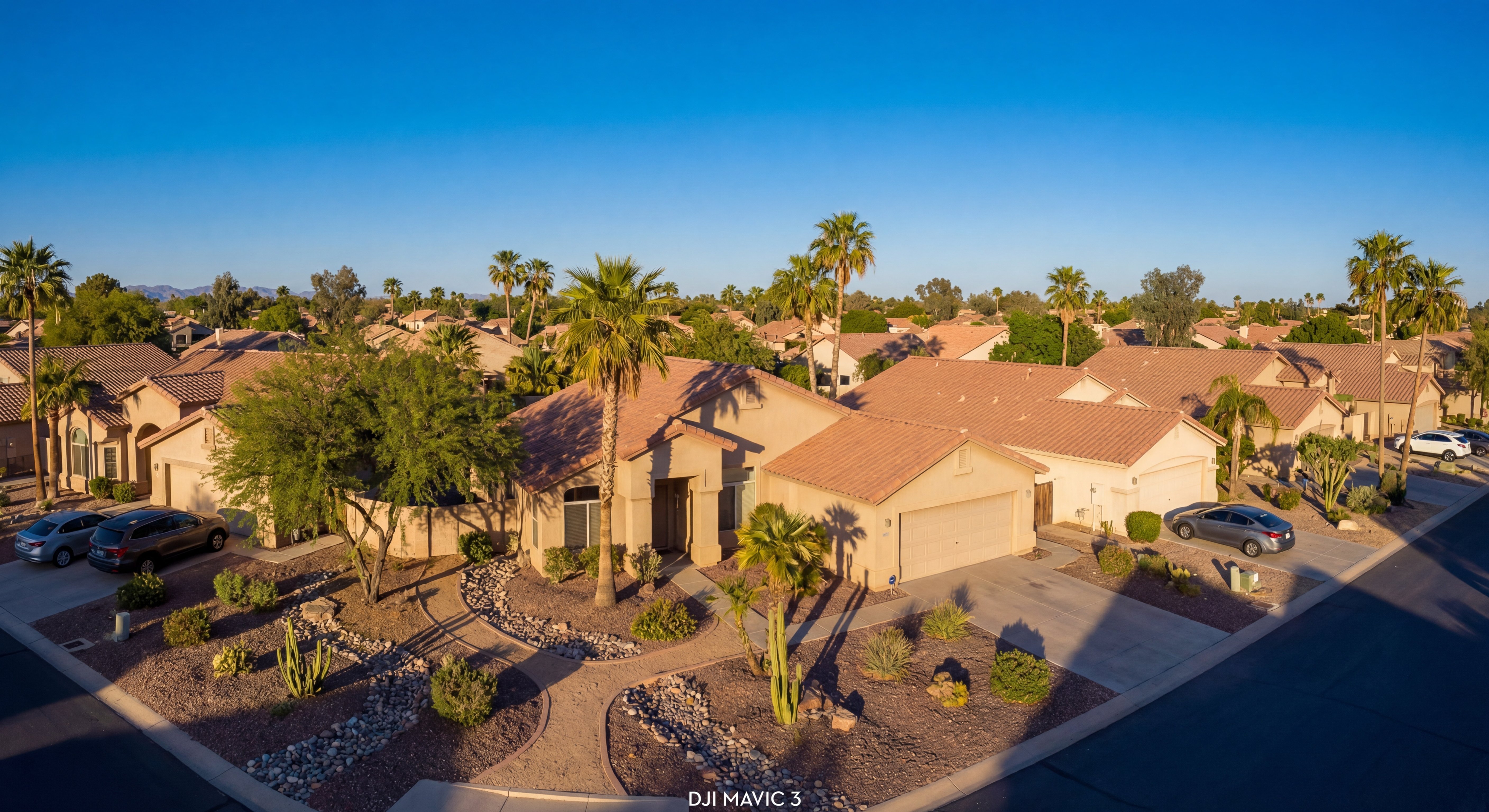 Phoenix metro aerial showing suburban stucco homes with desert landscaping and blue sky
